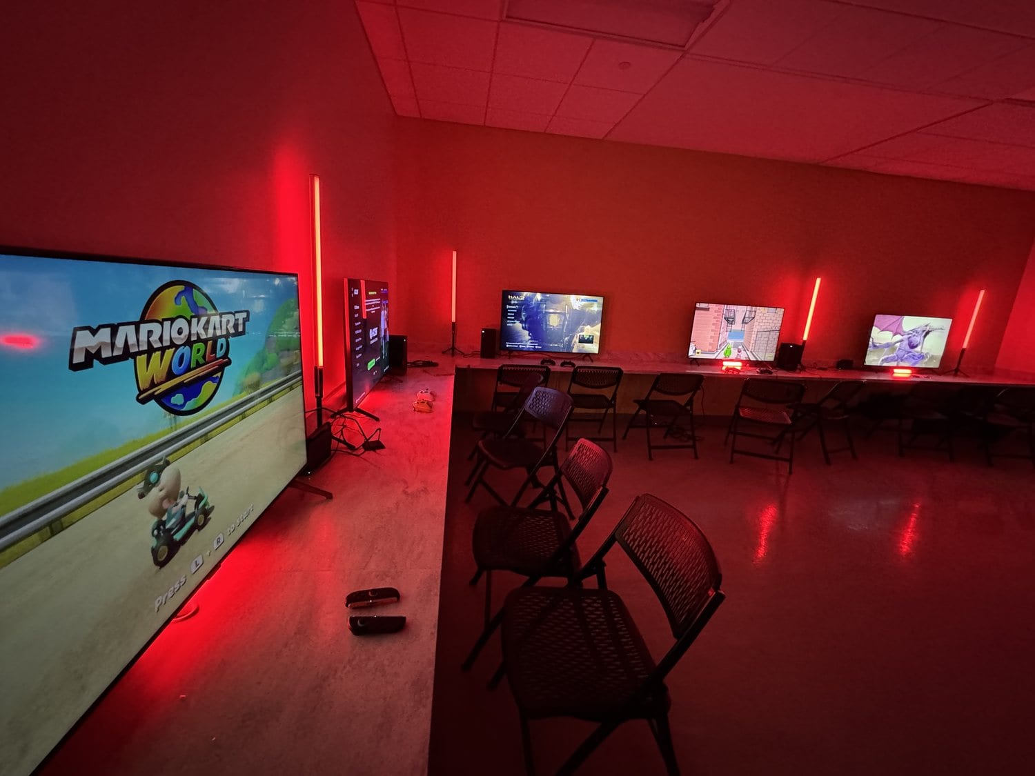 A Next Level Gaming mobile arena in a dark room with red LED lighting and Mario Kart on a big screen in the DMV
