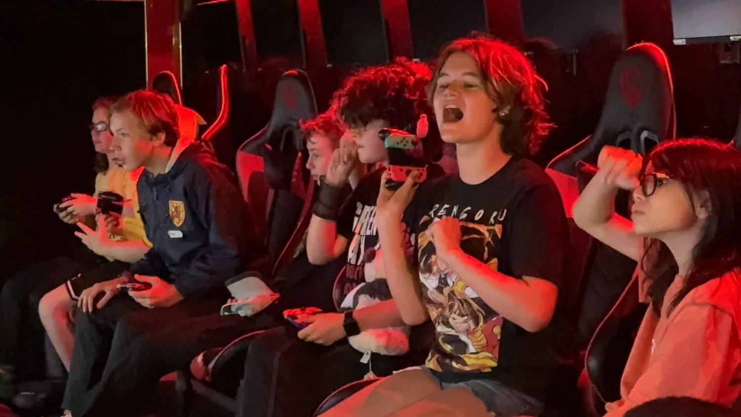 Players inside the Next Level Gaming theater holding controllers and playing across multiple screens