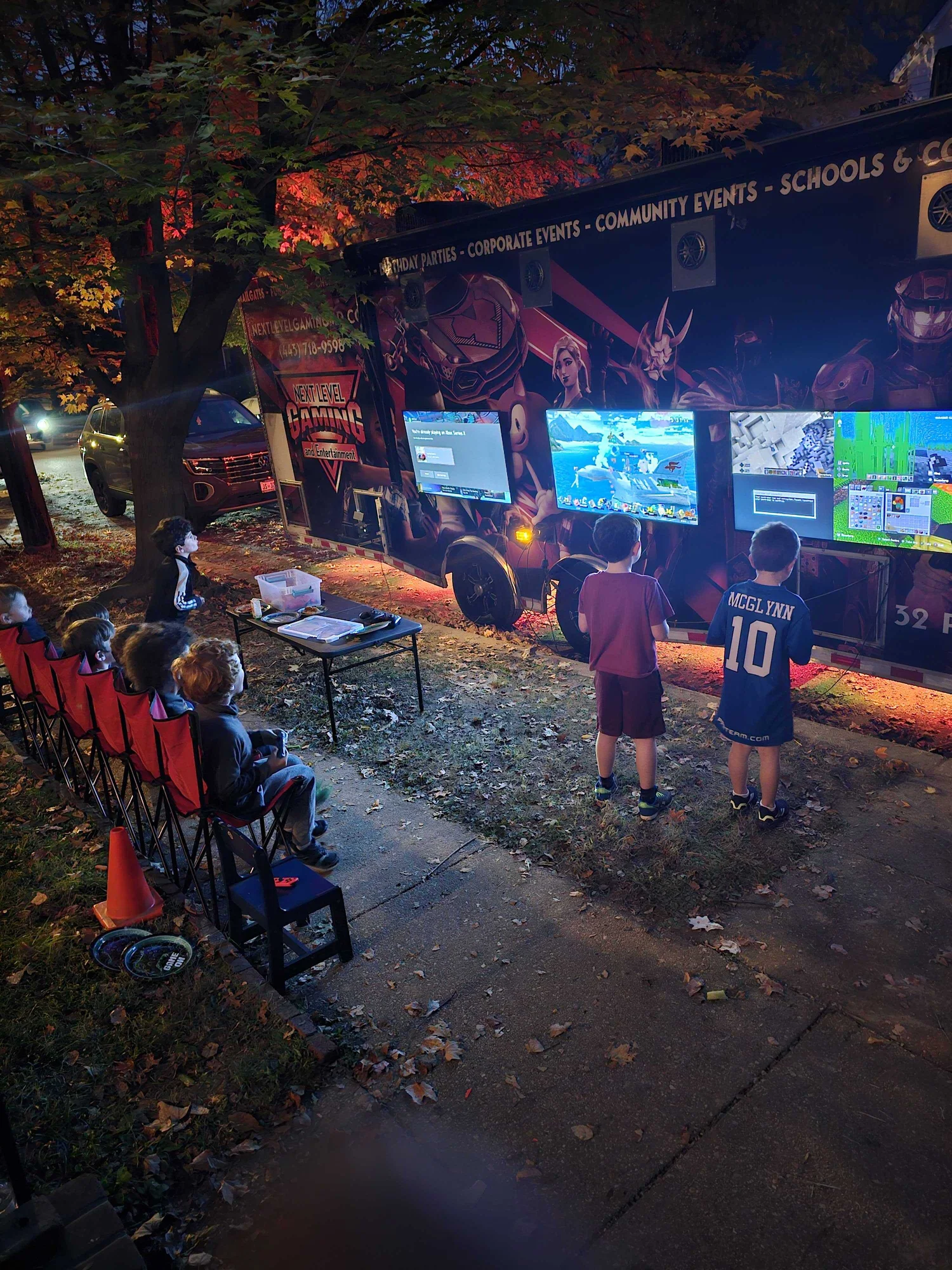 Next Level Gaming theater set up beside a house in the evening with players using the outdoor screens