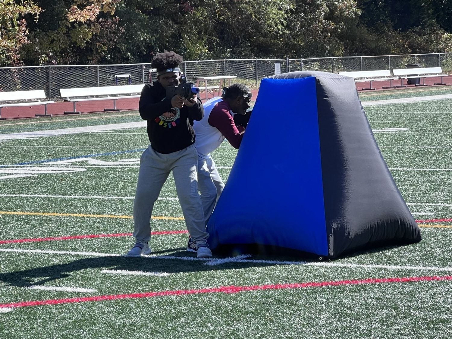 Players in an outdoor laser tag match on a turf field with inflatable obstacles at a Next Level Gaming event in the DMV