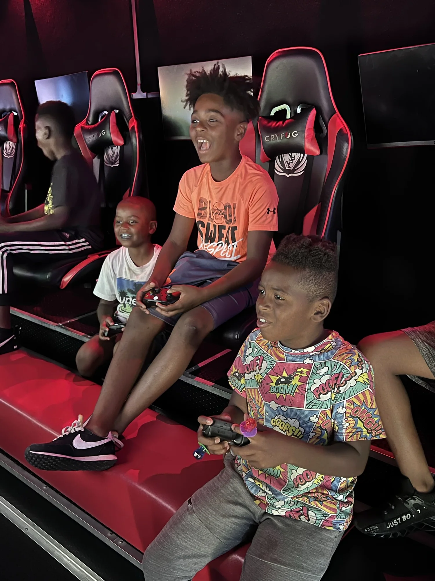 Players laughing together while holding controllers inside the game theater